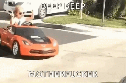 Little Girl Driving Red Toy Car Down Street GIF