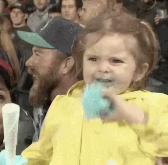 Little Girl Eating Cotton Candy in Crowd