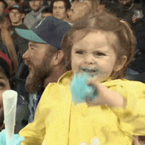 Little Girl Eating Cotton Candy in Crowded Stadium