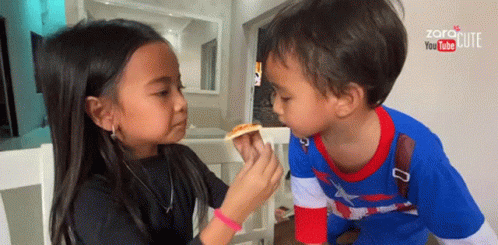 Little Girl Feeding Little Boy Slice of Pizza