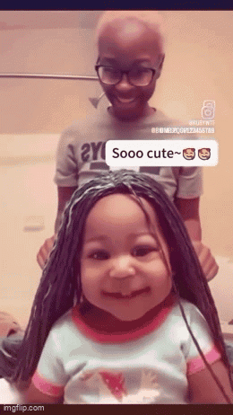 Little Girl in Braided Wig Smiling Next to Boy With Glasses