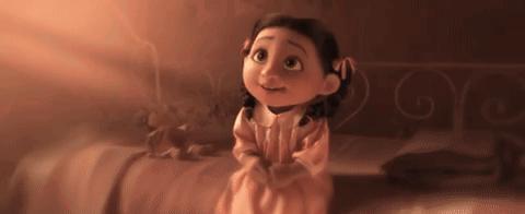 Little Girl in Pink Dress Sitting on Bed Looking Up