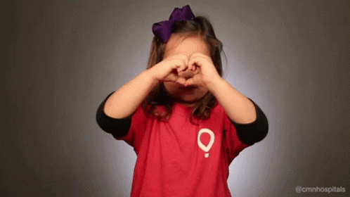 Little Girl in Red Shirt With O Making Heart Hands