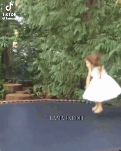 Little Girl in White Dress Jumping on Trampoline