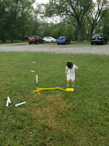 Little Girl In White Dress Playing With Rocket GIF