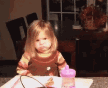 Little Girl Sitting at Table With Water Bottle