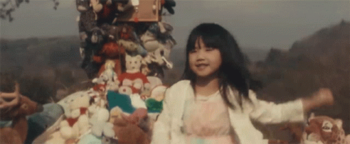Little Girl Standing in Front of Stuffed Animals and Toys