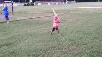 Little Girl Swinging Bat At Ball On Field GIF