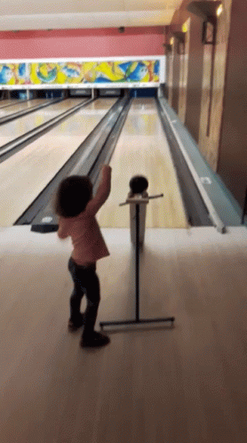 Little Girl Throwing Bowling Ball in Bowling Alley