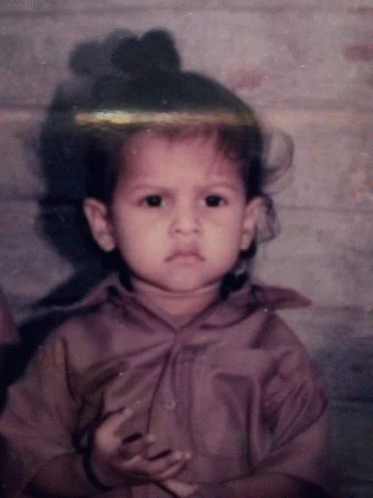 Little Girl With Bun On Head Looking At Camera GIF