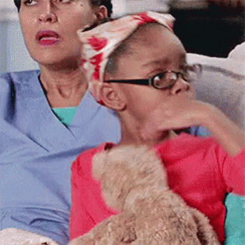 Little Girl With Glasses Holding Teddy Bear Beside Woman GIF
