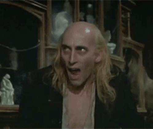 Long Blonde Hair Bald Man Shirtless in Dark Room