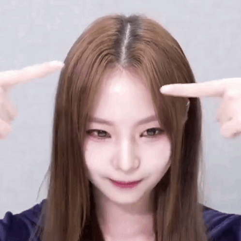 Long Brown Haired Woman Pointing at Forehead