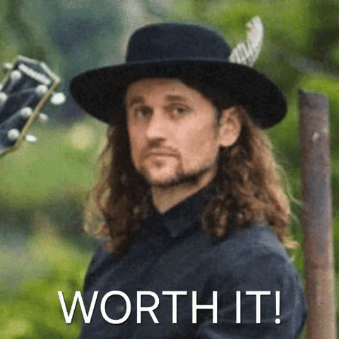 Long Hair Man in Black Hat Holding Guitar Saying Worth It