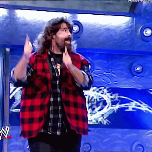 Long Haired Bearded Man in Red and Black Plaid Shirt at WWE Logo
