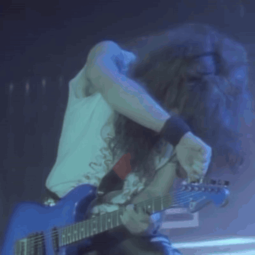 Long Haired Man Playing Blue Guitar in Dark Room
