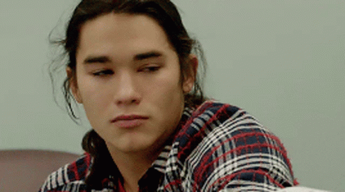 Long-Haired Young Man In Plaid Shirt Looking At Camera GIF