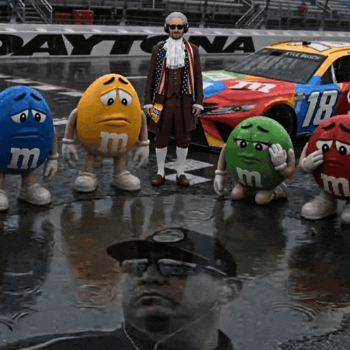 M&Ms Standing In Front Of Daytona Race Car GIF