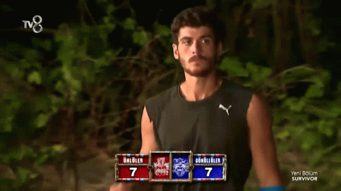 Man Adjusting Hair in Front of Survivor TV