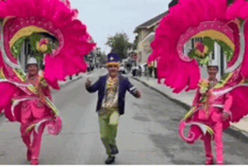 Man and Two Women in Pink Costumes Walking Down Street