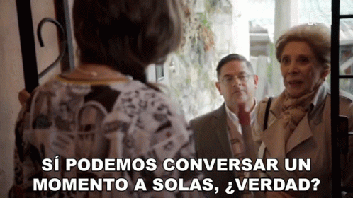 Man and Two Women Standing in Front of a Door Saying Si Podemos Conversar un Momento a Solas Verdad