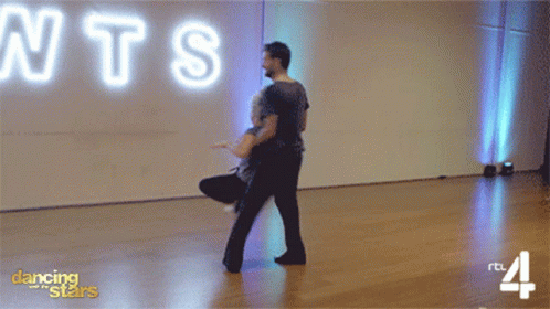 Man and Woman Dancing in Front of Neon Sign Saying NTS