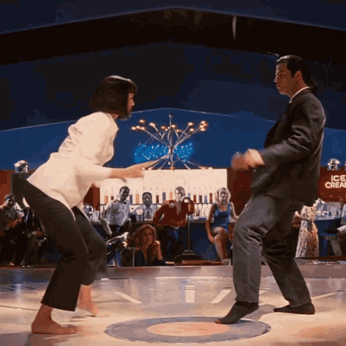 Man and Woman Dancing on Stage in Front of Ice Cream Sign