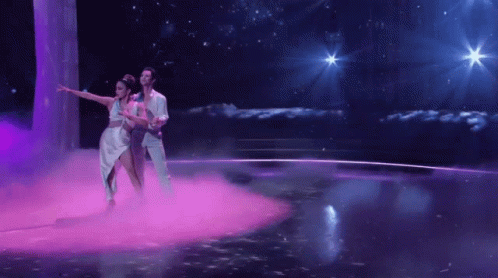 Man and Woman Dancing on Stage With Purple Smoke