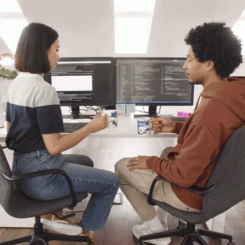 Man And Woman Drinking Coffee At Two Monitors Mugs Saying Milk GIF