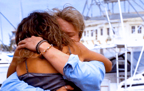 Man and Woman Hugging in Front of Building Saying Pa