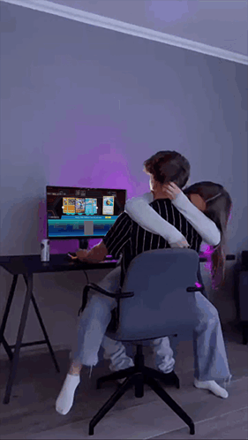 Man and Woman Hugging in Front of Computer Monitor