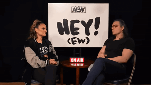 Man and Woman in Front of Hey Ew Sign