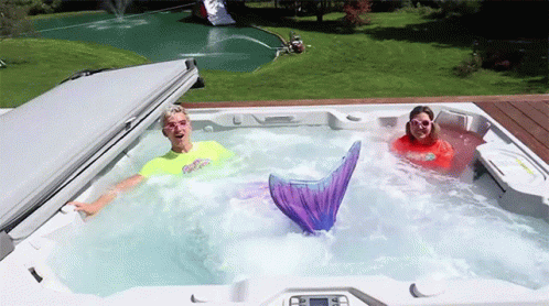 Man and Woman in Hot Tub With Mermaid Tail