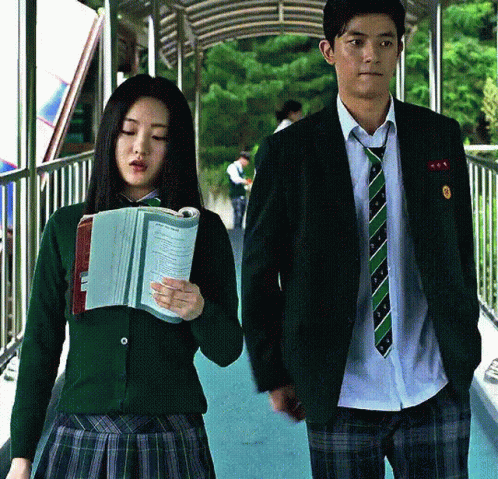 Man and Woman in School Uniforms Walking Down Bridge