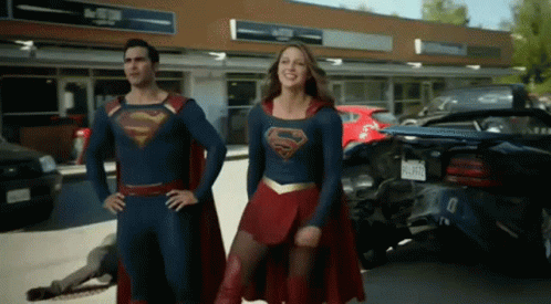 Man And Woman In Superman Costumes Standing In Front Of Store GIF