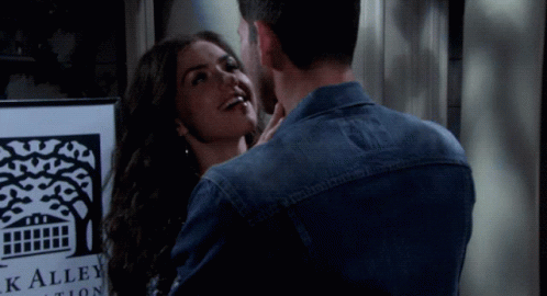 Man And Woman Kissing In Front Of Black Alley Auction Sign GIF