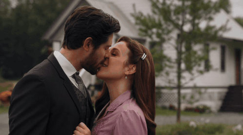 Man and Woman Kissing in Front of House