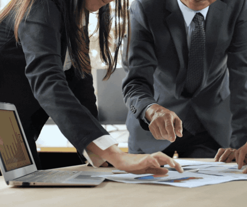 Man and Woman Looking at Laptop and Papers