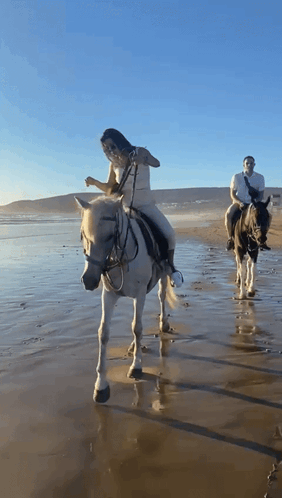 Man and Woman Riding Horses on Beach