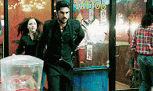 Man And Woman Running From Tattoo Shop GIF