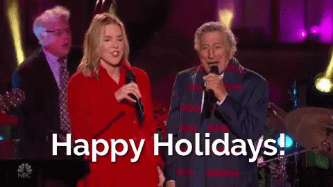 Man and Woman Singing Into Microphones Happy Holidays