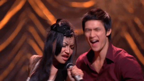 Man and Woman Singing Into Microphones on Stage