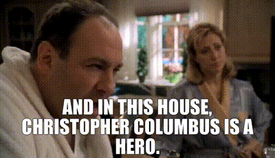 Man And Woman Sitting At Table With House And Columbus Text GIF
