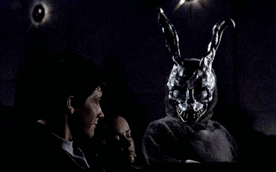 Man and Woman Sitting in Dark Room With Rabbit Mask
