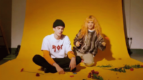 Man And Woman Sitting In Front Of Yellow Background GIF