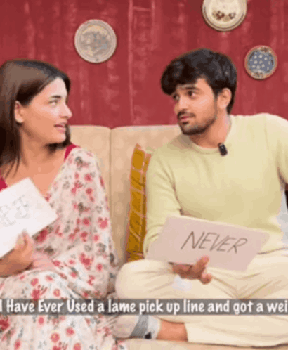 Man and Woman Sitting on Couch Holding Never Card