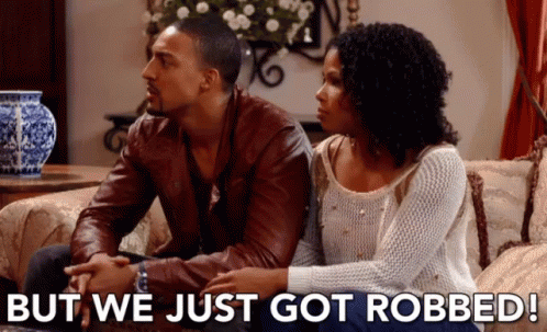 Man and Woman Sitting on Couch Saying But We Just Got Robbed