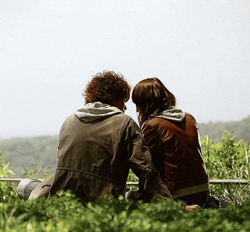Man and Woman Sitting on Ledge Looking at Sky