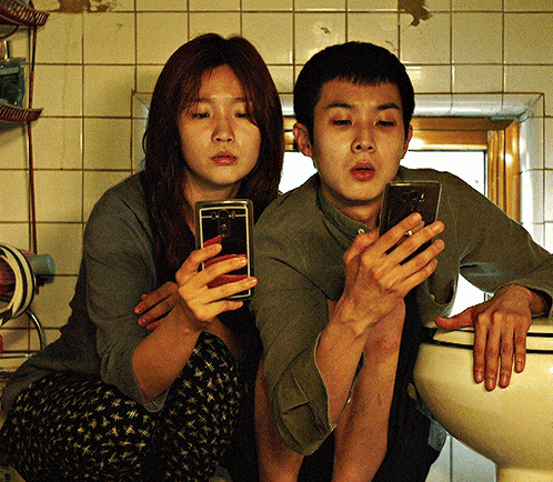 Man And Woman Sitting On Toilet Using Phones GIF