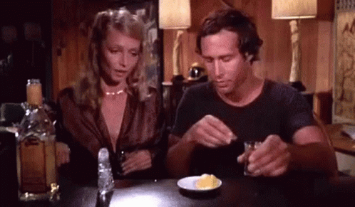 Man and Woman Sitting with Alcohol and Food
